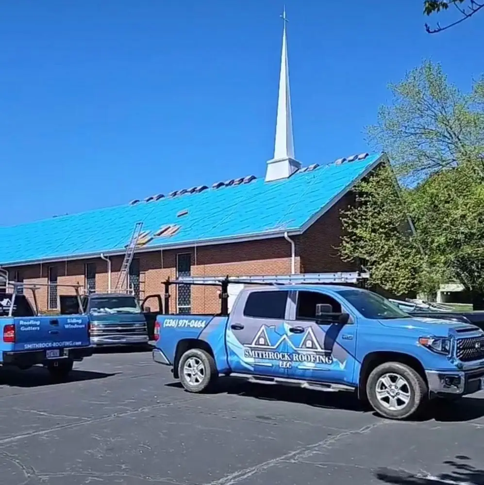 Smithrock Roofing trucks at a church reroofing project with underlayment installed on the sanctuary roof