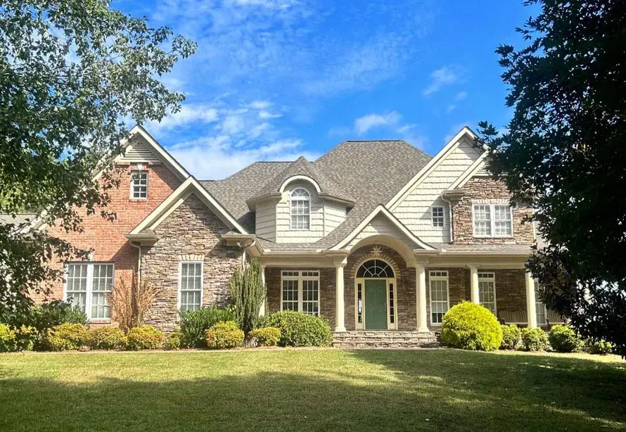 Large custom home with stone and siding exterior and freshly installed architectural shingle roof