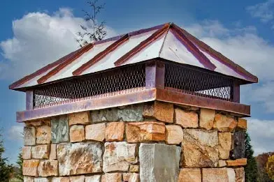 Copper hip ridge chimney cap on a stone chimney